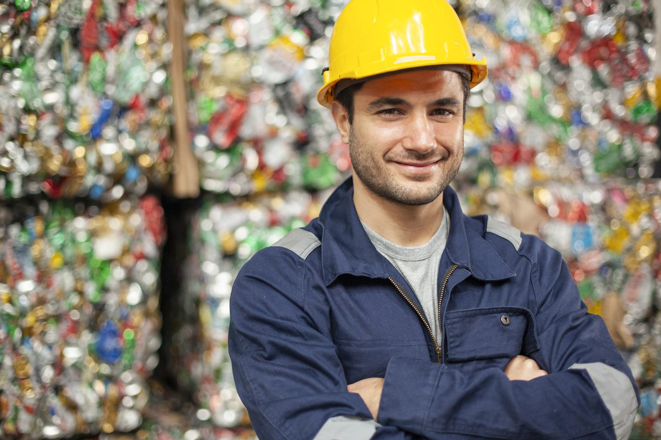 Smiling male recycling plant employee with arms crossed looking at the camera